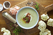 Cauliflower soup with ingredients on a wooden surface