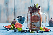 Glass jar of healthy breakfast with muesli, pudding with chia seeds, fresh fig and berries