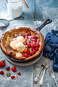 Baby dutch pancake in a skillet with fresh berries and ice cream
