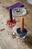 Candles in wine glasses filled with rose hips and viburnum berries