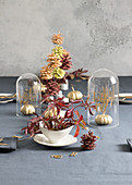 Herbstlich gedeckter Tisch mit bemalten Kürbissen und Zapfen