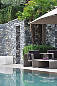 Modern seating area with stone walls next to pool