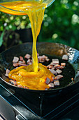 Scrambled eggs with bacon cooking outdoors