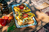 Toast with scrambled eggs, tomatoes and chives on a garden table