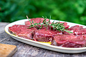 Raw beef loin steaks with rosemary in a garden kitchen