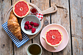 Breakfast with croissants, jam, raspberries and grapefruit