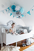 Girl playing with doll on wooden bed in child's bedroom