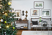Geschmückter Tannenbaum im Wohnzimmer mit Polsterbank und Bildergalerie