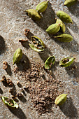 Cardamom pods with ground cardamom on stone from overhead
