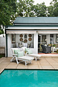 Two loungers on terrace next to swimming pool with open terrace doors leading into living room