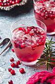 Erfrischungsgetränk mit Cranberries, Eis und Rosmarin
