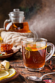 Glass cup of hot tea with mint, honey, ginger and lemon