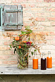 Herbstlicher Blumenstrauß und drei Saftflaschen vorm Haus