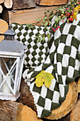 Hand-knitted blanket and cushion on stacked firewood