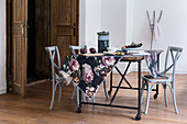 Geblümter Stoff auf einem rustikalen Tisch mit grauen Bistrostühlen