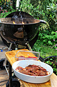 Grilled meat in front of a barbecue in a garden