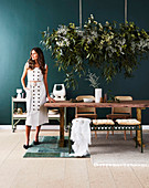 Brünette Frau am Esstisch mit Massivholz-Tischplatte, darüber Zimmerpflanze