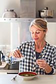 Woman adding fresh cream to a soup