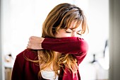 Woman covering her face with his arm to sneeze