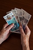 Elderly woman holding British banknotes