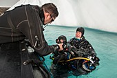 SCUBA divers returning to boat after diving next to iceberg