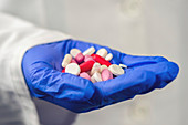 Various pills held in gloved hand