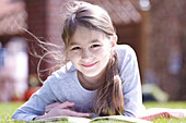 Girl lying on grass reading