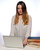 Woman using laptop with books