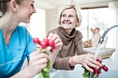 Carer washing radishes with woman