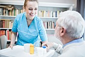 Carer and senior man with medicine bottles