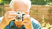 Elderly man taking pictures with camera