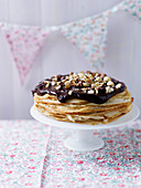 A crepe cake topped with chocolate and hazelnuts