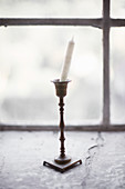 Candle stuck crookedly in classic brass candlestick