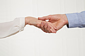 A woman's hand in a man's hand (body language: insecure handshake)