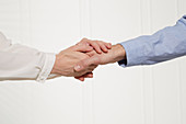 A woman's hands holding a man's hand (body language: appreciative handshake)