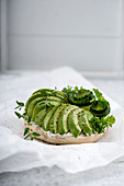 A sesame bagel with almond cheese, avocado, cucumber and fresh herbs (vegan)