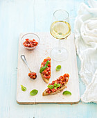 Bruschetta mit Tomaten und Basilikum serviert mit einem Glas Weißwein