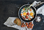 Pan of fried eggs, bacon and cherry-tomatoes with bread