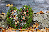 Moss love-heart decorated with Gaultheria berries, poppy seedheads and silver ragweed