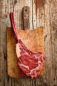 A raw tomahawk beef steak on a wooden board (top view)