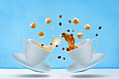 Flying cups of coffee with sugar and coffee beans on a blue background