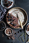 Chocolate tart topped with blackberries and blueberries on a vintage pie plate, sliced