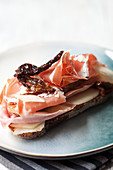 An open sandwich topped with Parmesan, pears, radicchio, dried tomatoes and Parma ham