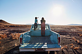 Mutter und Sohn stehen auf der Ladefläche eines Pick-ups (Wüstenlandschaft, Arizona, USA)