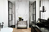 Waschtisch aus schwarzem Marmor in luxuriösem Bad, Wand mit weißer Marmor-Verkleidung