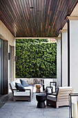 Sofa, Sessel und Baumstamm-Hocker auf überdachter Terrasse