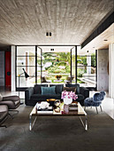 Blue upholstered sofa, fur-look chair and coffee table in open living room, glass patio door in background