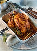 Roast chicken in a roasing tin with a linen cloth on a stone platter