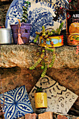 Tiles, succulents and decorative plate on rustic stone shelf