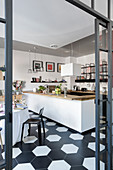 Blick in Küche mit Küchentheke und Essbereich auf schwarz-weißem Fliesenboden